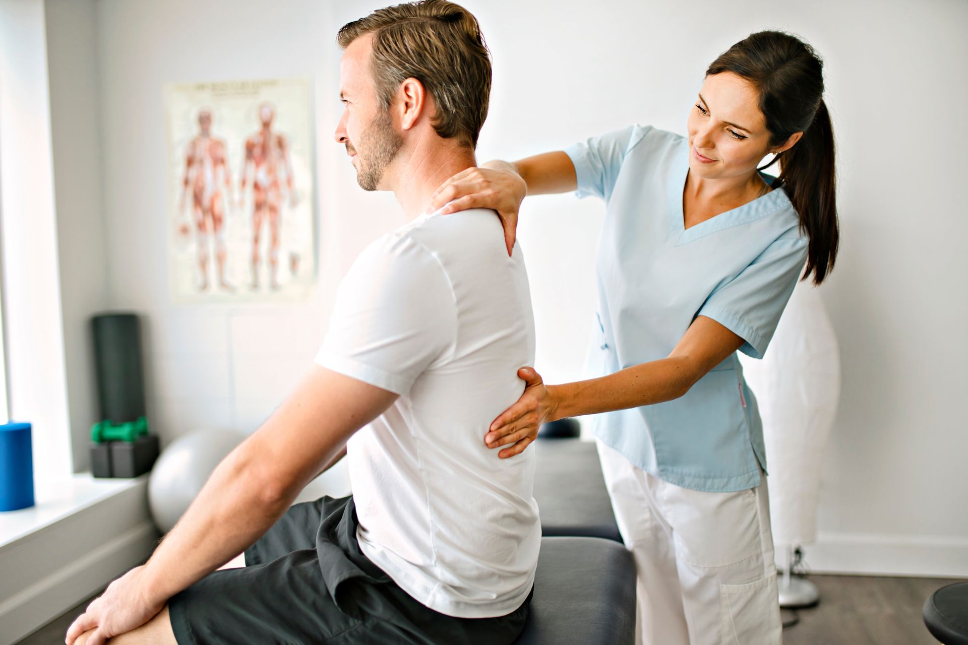 Diversified Technique Chiropractor adjusting a seated male patient's shoulder in a clinic.