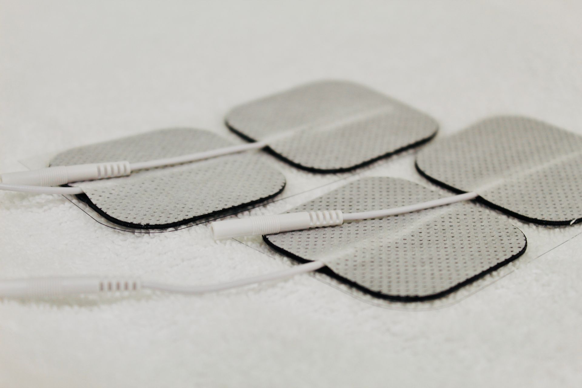 Four white square TENS electrode pads. 