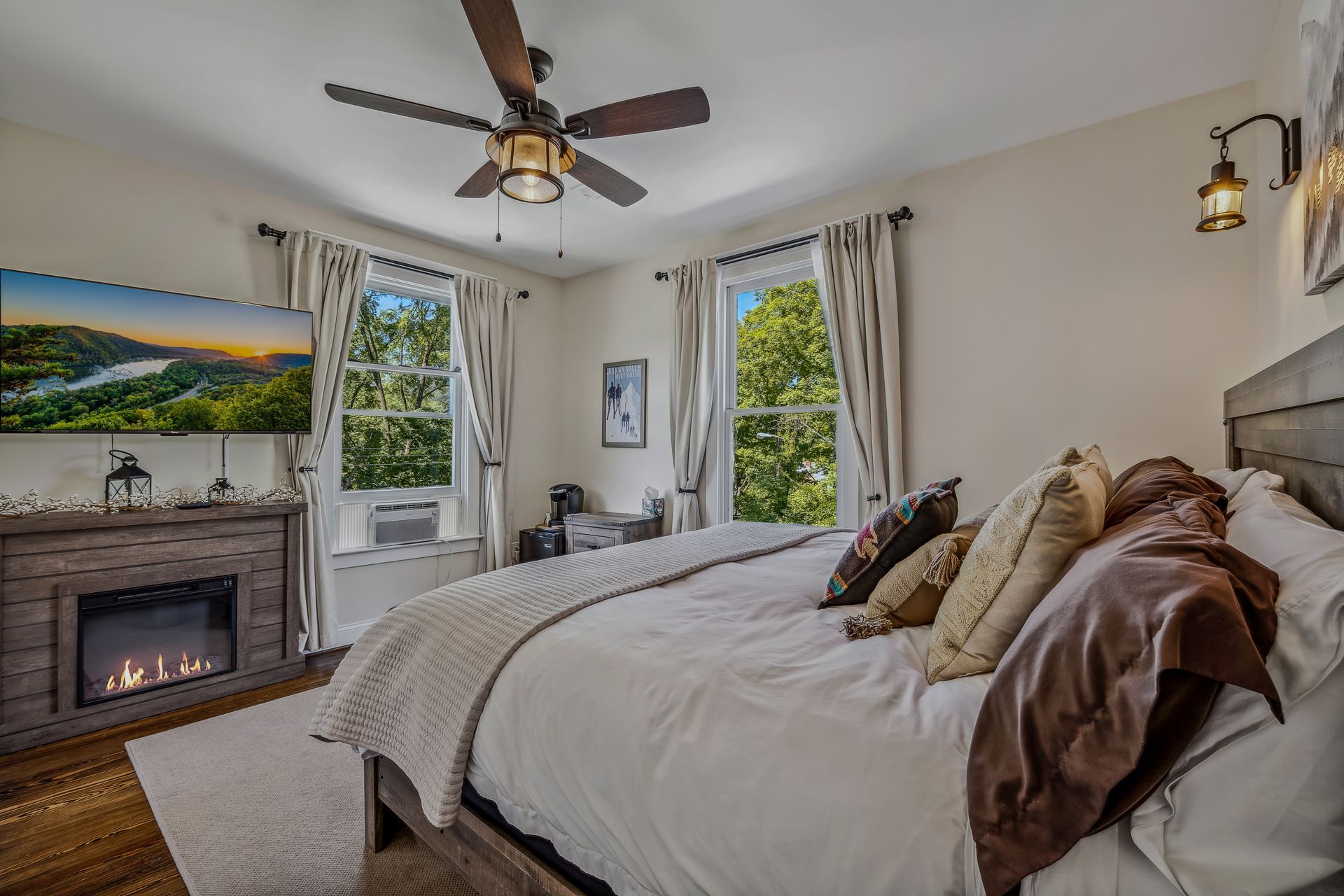A bedroom with a king size bed , fireplace and ceiling fan.