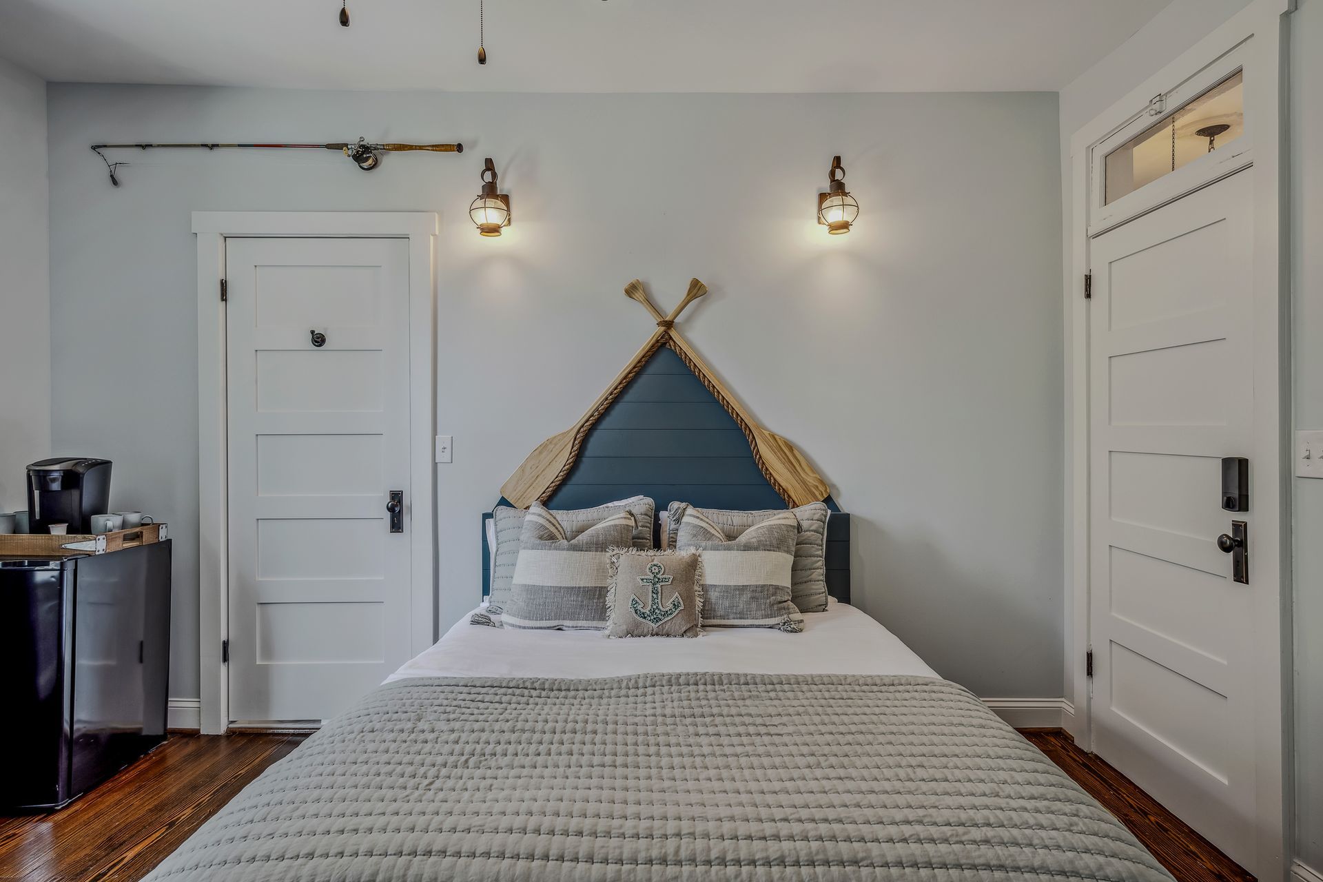 A bedroom with a bed , oars on the wall , and a door.