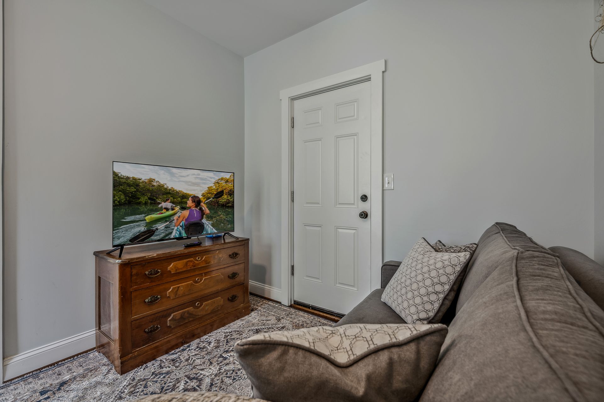 A living room with a couch , dresser , and television.