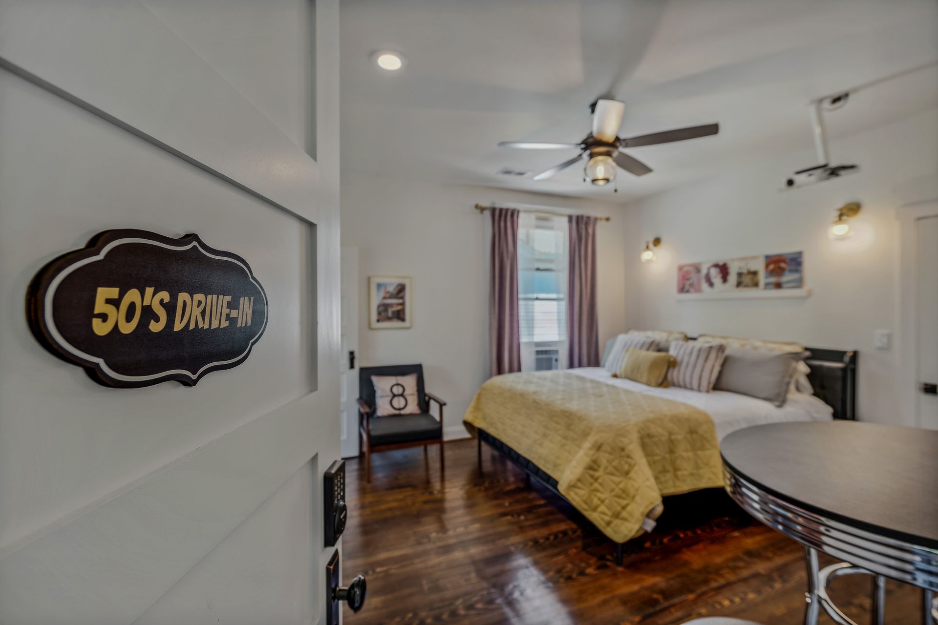 A bedroom with a bed , chair , table and ceiling fan.