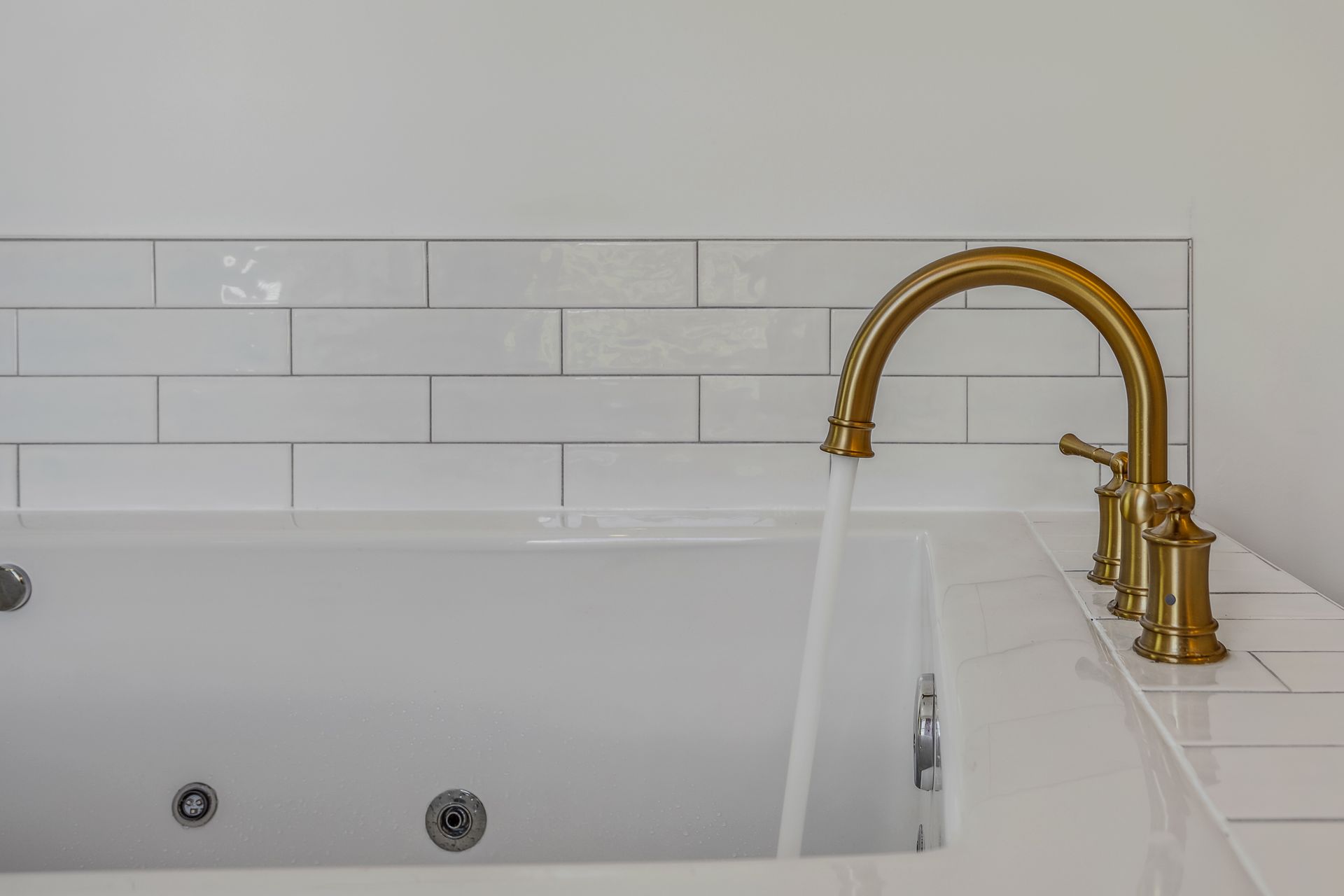 A bathtub with a gold faucet is filled with water.