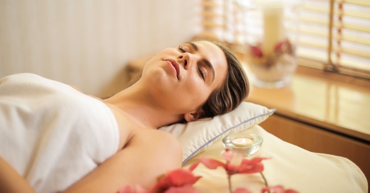 A woman is laying on a bed in a spa with her eyes closed.