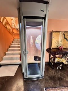 Indoor stairlift beside a staircase and dining table in a home with orange walls and dark floors