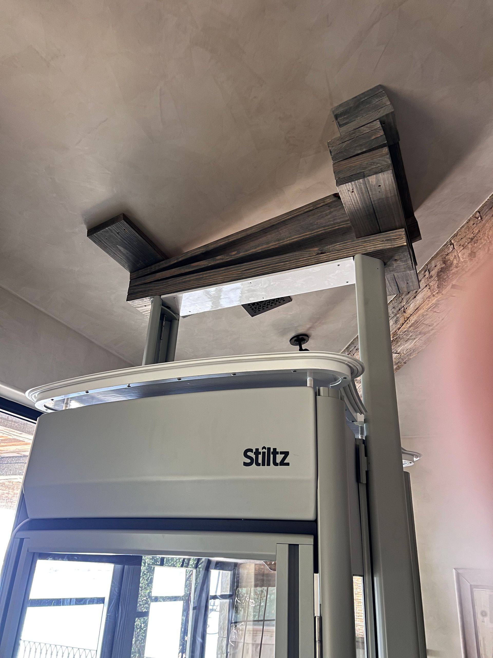 Indoor Stiltz Homelift with a gray top platform attached to a ceiling beam above a doorway.