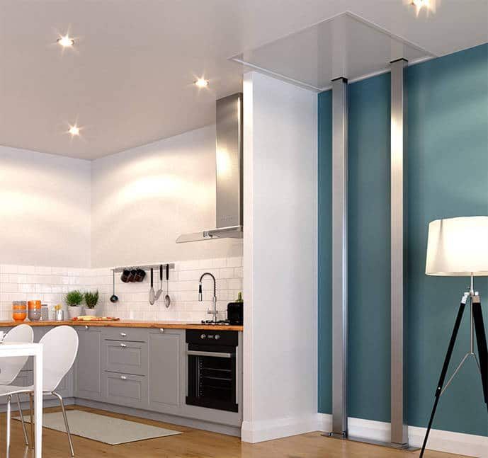 Modern kitchen adjacent to a blue wall with two tall, thin floor-to-ceiling metal supports connected to a ceiling panel.