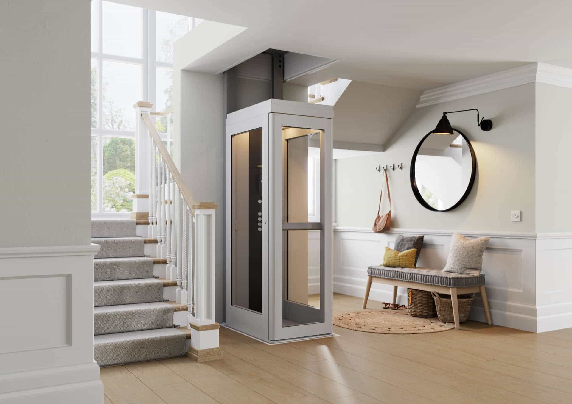 A light gray residential elevator installed in a modern home entryway next to a carpeted staircase and a wooden bench.
