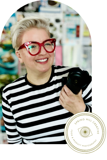 A woman wearing glasses and a striped shirt is holding a camera