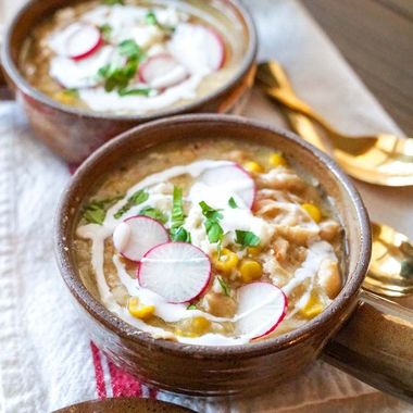 Two bowls of soup with radishes and sour cream on a table