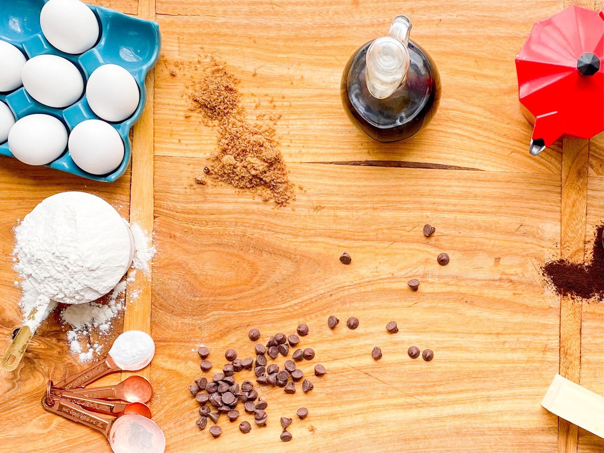 Ingredients for baking are laid out on a wooden table.