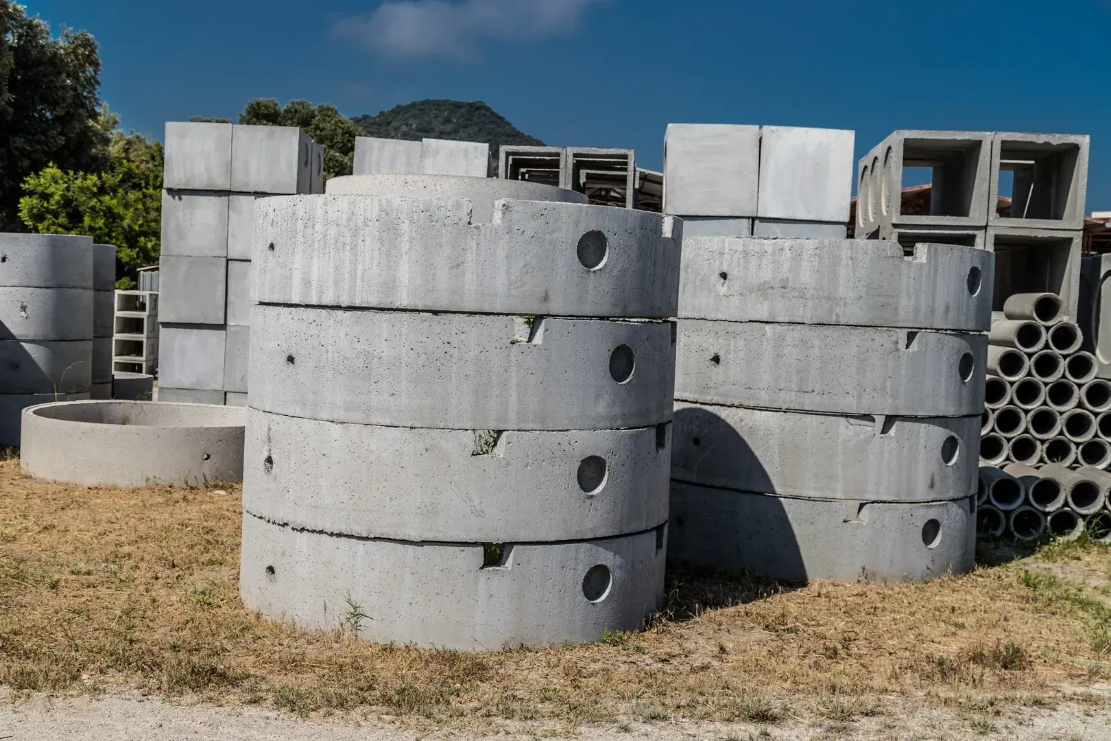 Blocchi di cemento e pallet impilati all'interno di un magazzino aperto su un lato con tetto in metallo.