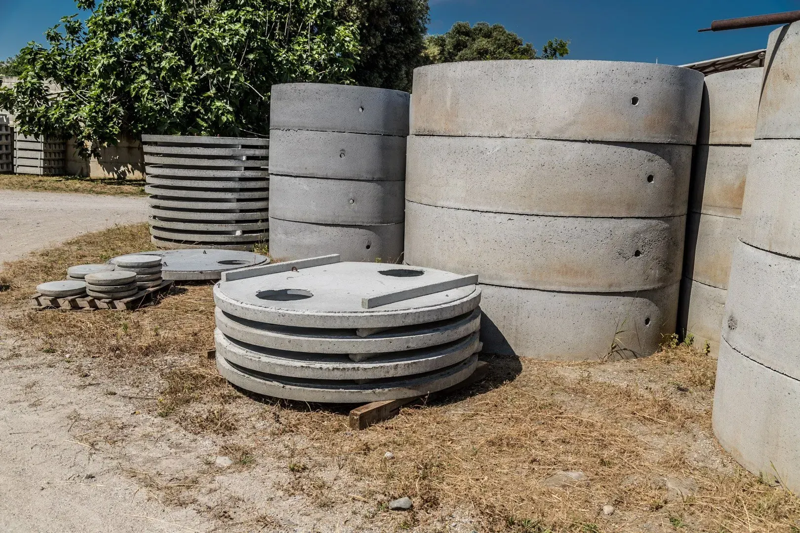 Pallet di blocchi di cemento imballati, impilati in un'area di stoccaggio esterna contro un muro di cemento.