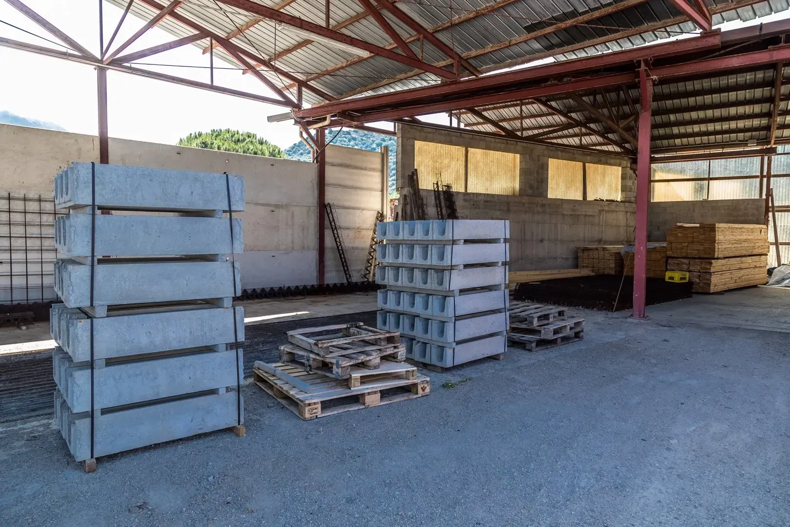 Pile di grandi tubi e anelli di cemento grigio all'aperto su terreno asciutto