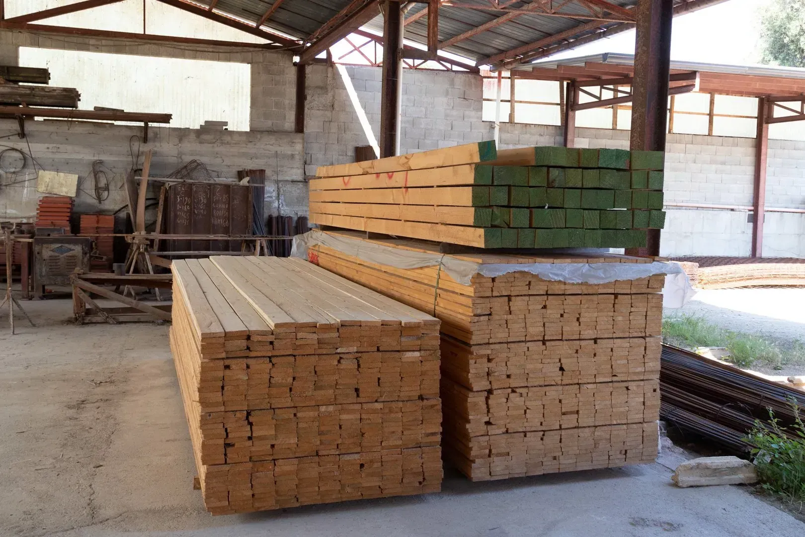 Pannelli da costruzione bianchi impilati e appoggiati a un muro all'aperto su terreno asciutto.