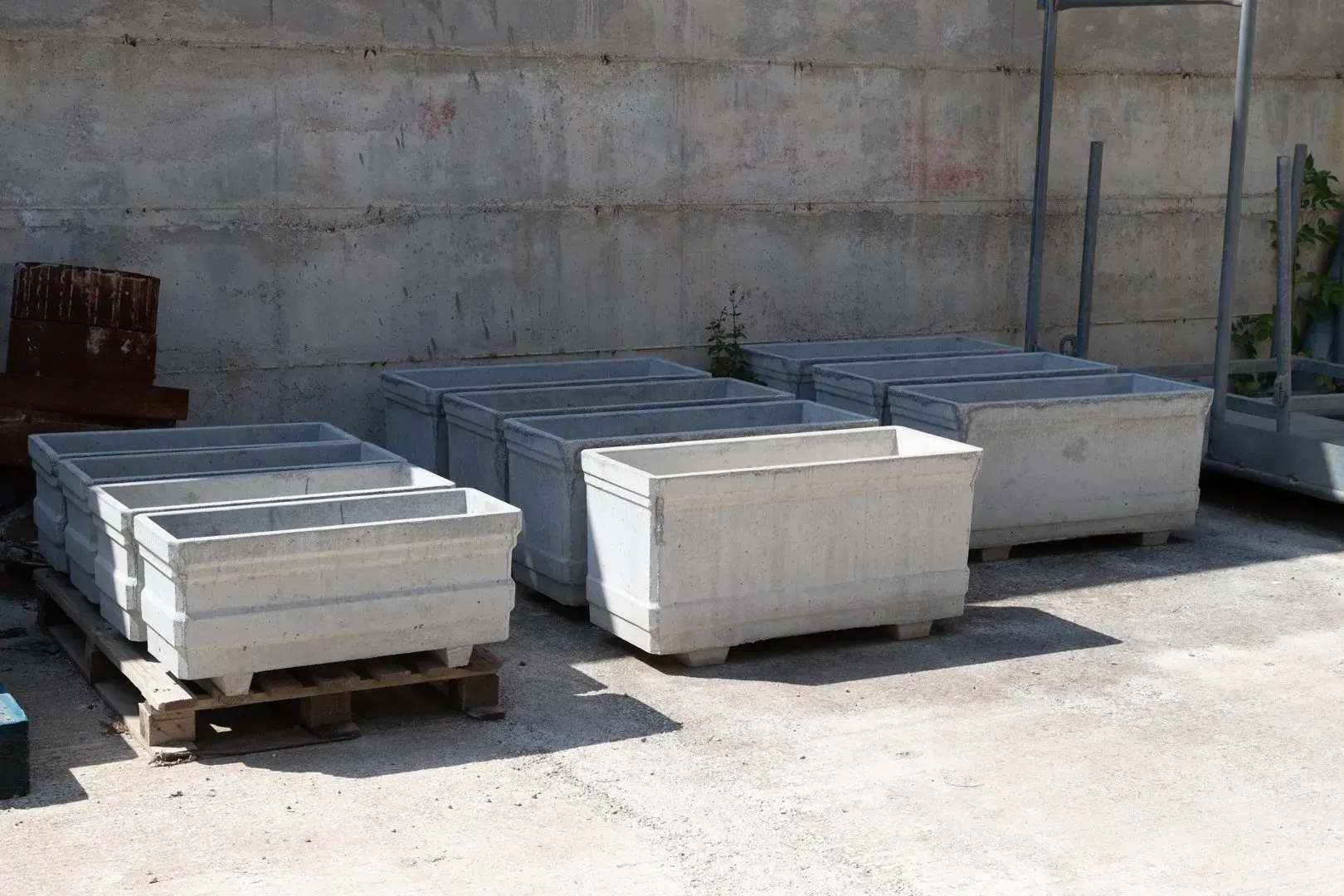 Pile di assi di legno in un magazzino aperto, con tavole marroni e verdi su pallet.