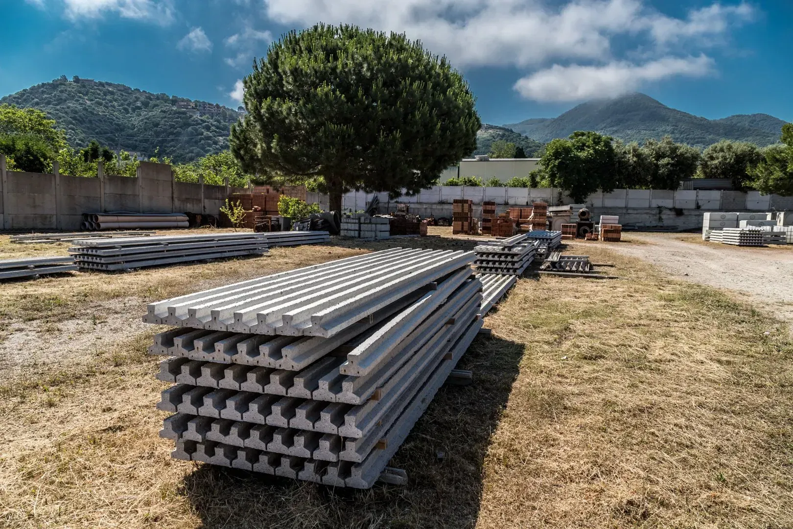 Blocchi e lastre di cemento impilati in un cantiere edile all'aperto.