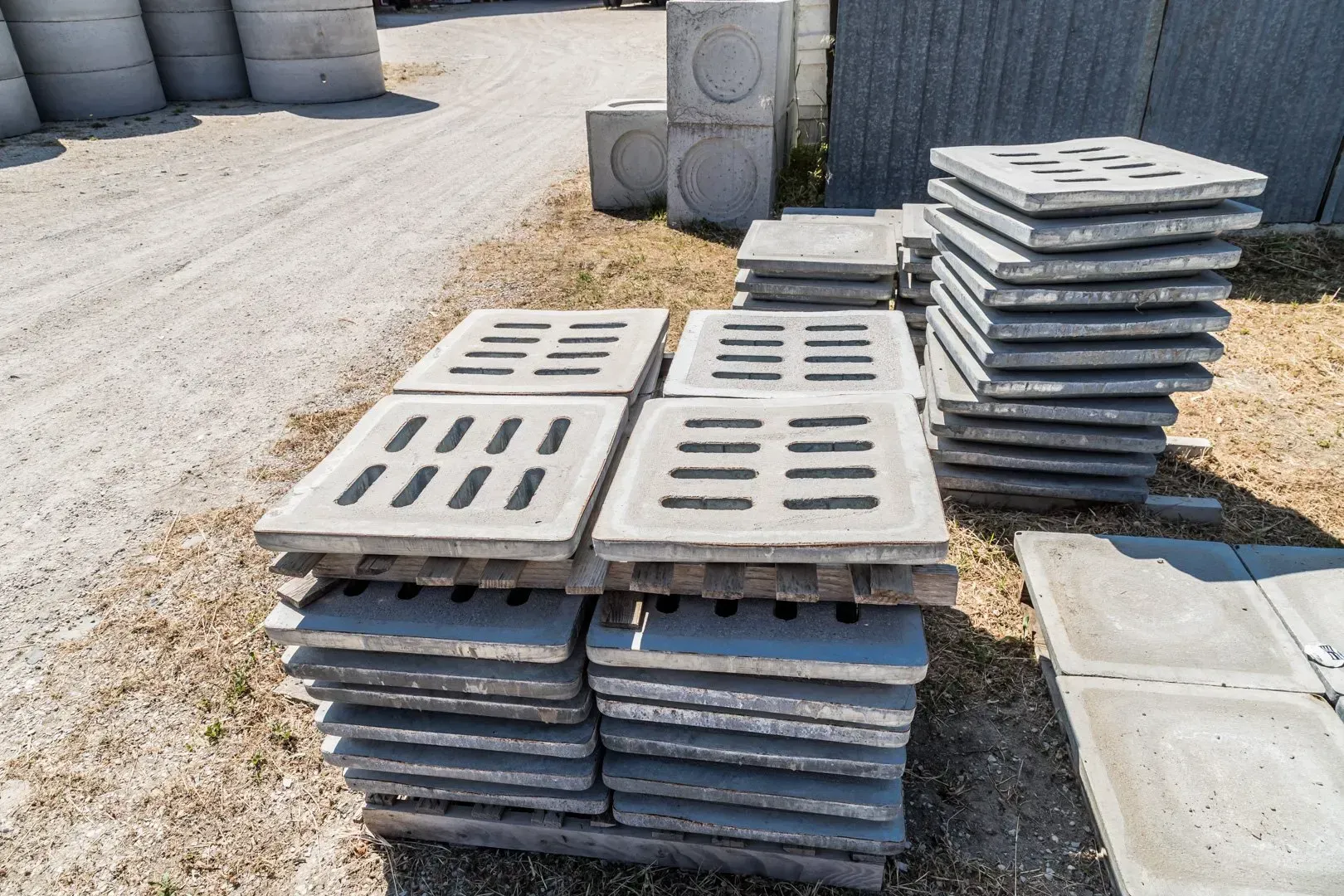 Blocchi di cemento impilati in un cantiere edile accanto ad anelli di metallo e pallet.