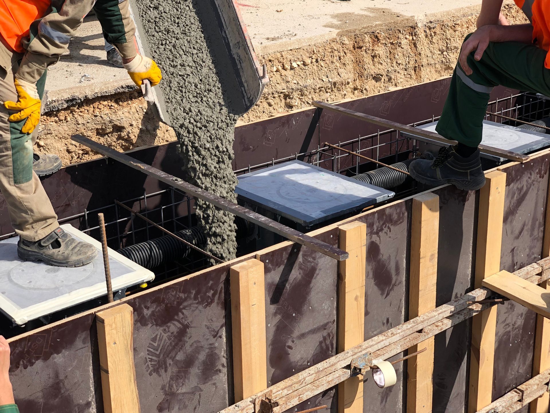Des ouvriers coulent du béton dans un coffrage en bois sur un chantier de construction