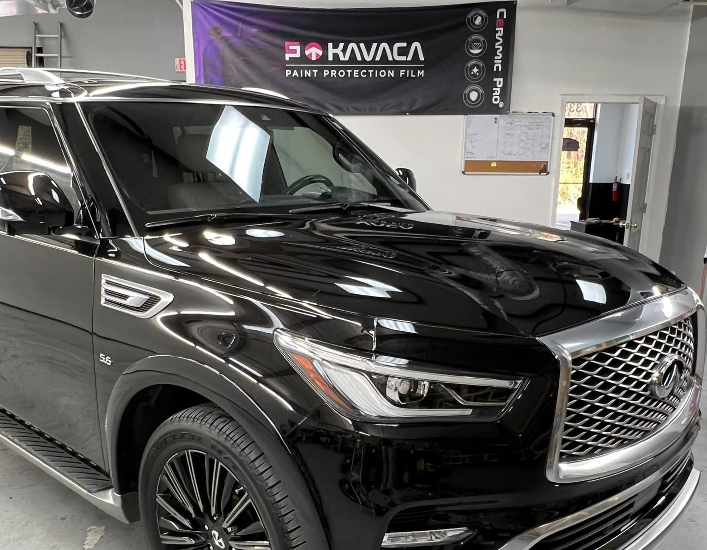 Black SUV in a showroom with shiny paint and a large chrome grille