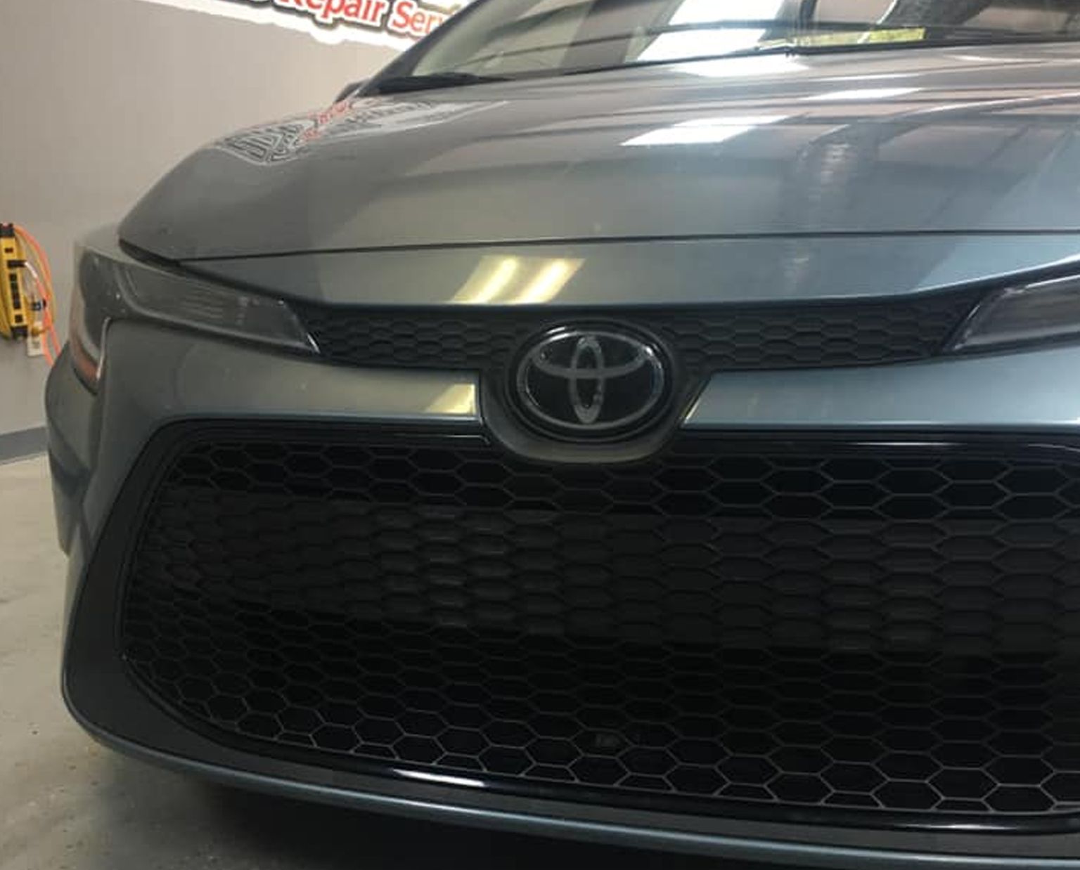 Front view of a gray Toyota car with a black grille in a garage