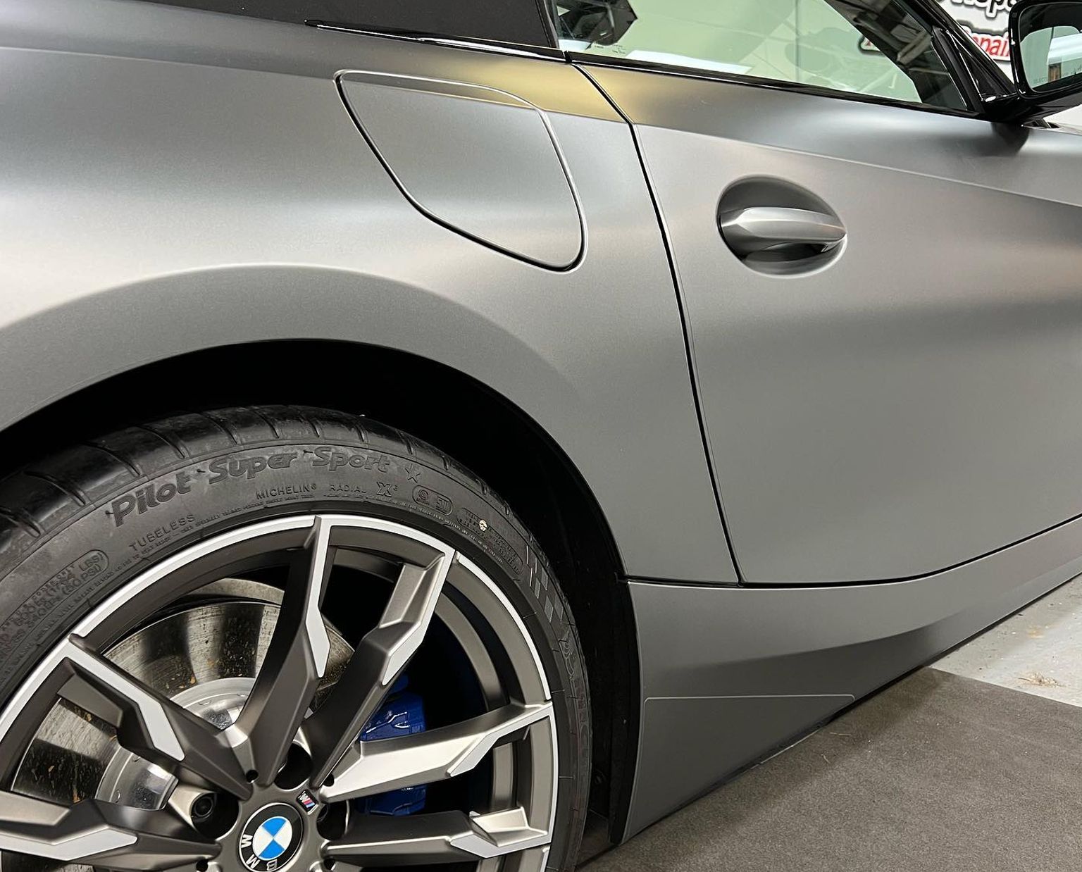 Close-up of a silver BMW rear quarter panel and wheel in a parking garage