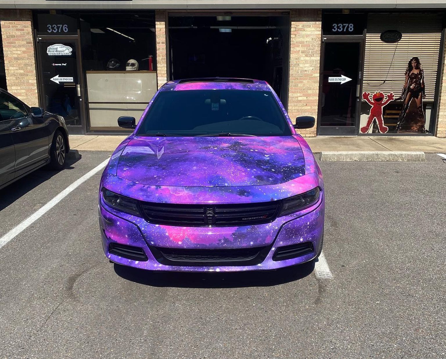 Purple galaxy-wrapped car parked outside a storefront, centered in the frame.