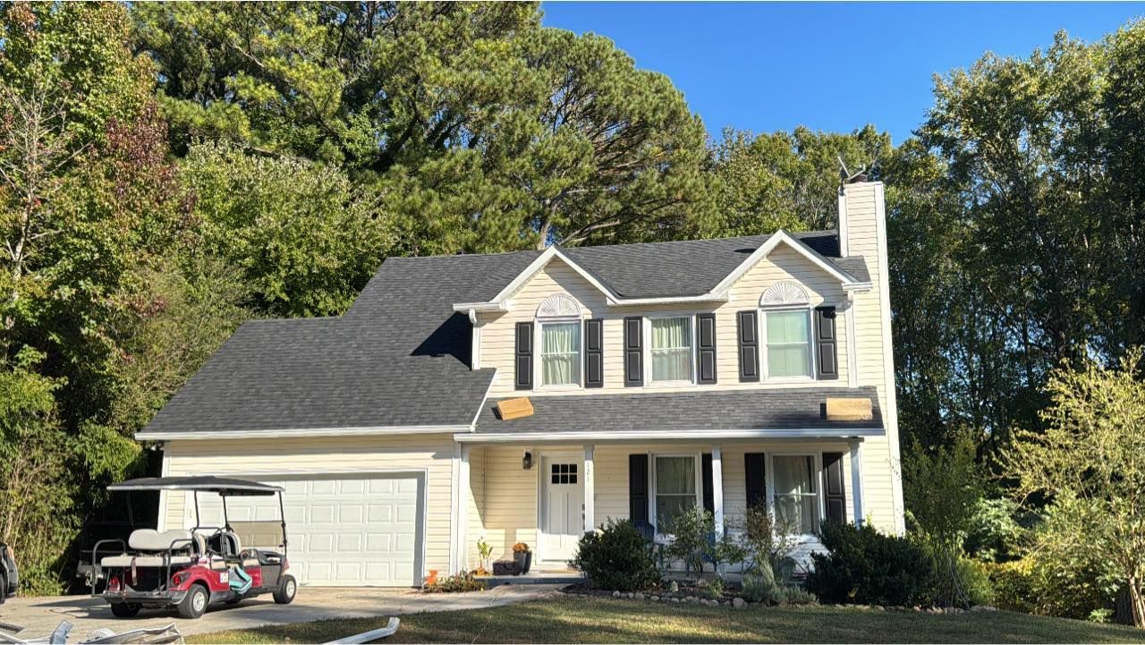 Two-story beige house with black shutters, gray roof, white trim, and a golf cart in the driveway.