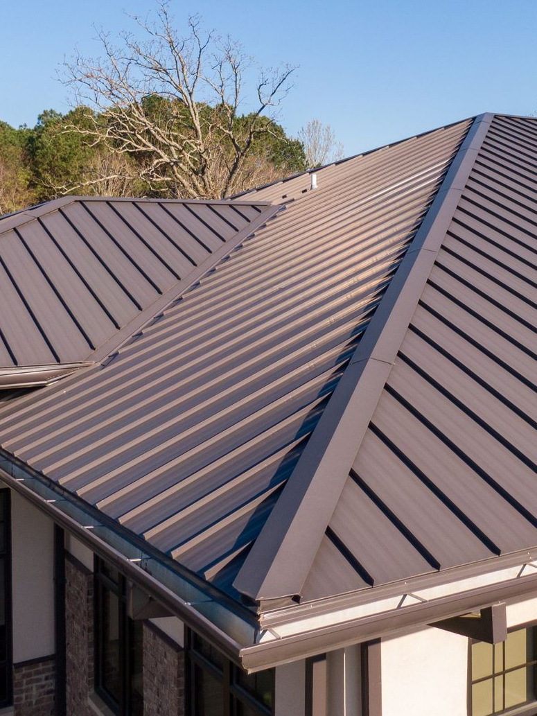 Brown metal roof on a building, angled view, against a clear blue sky.