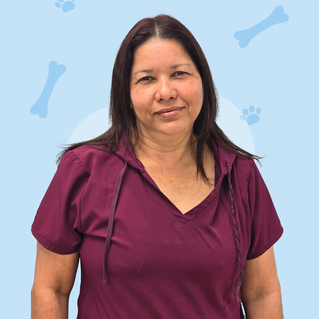 A woman in a purple shirt is standing in front of a blue background with bones and paw prints.
