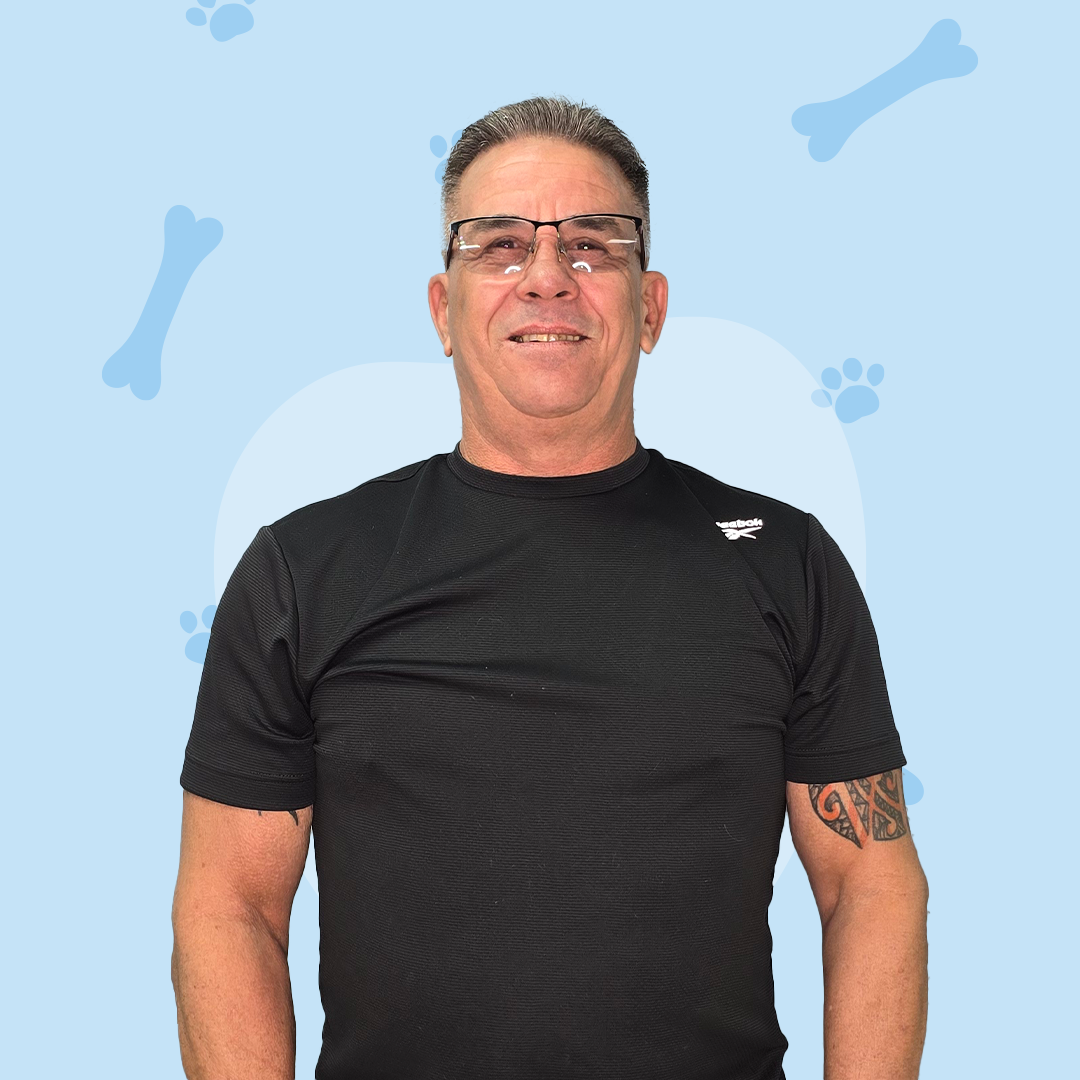 A man wearing glasses and a black shirt is standing in front of a blue background with bones and paw prints.