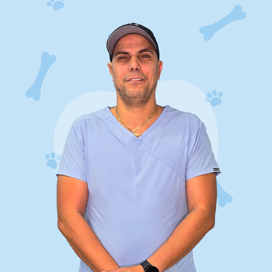 A man in a blue scrub top and hat is standing in front of a blue background with bones and paw prints.