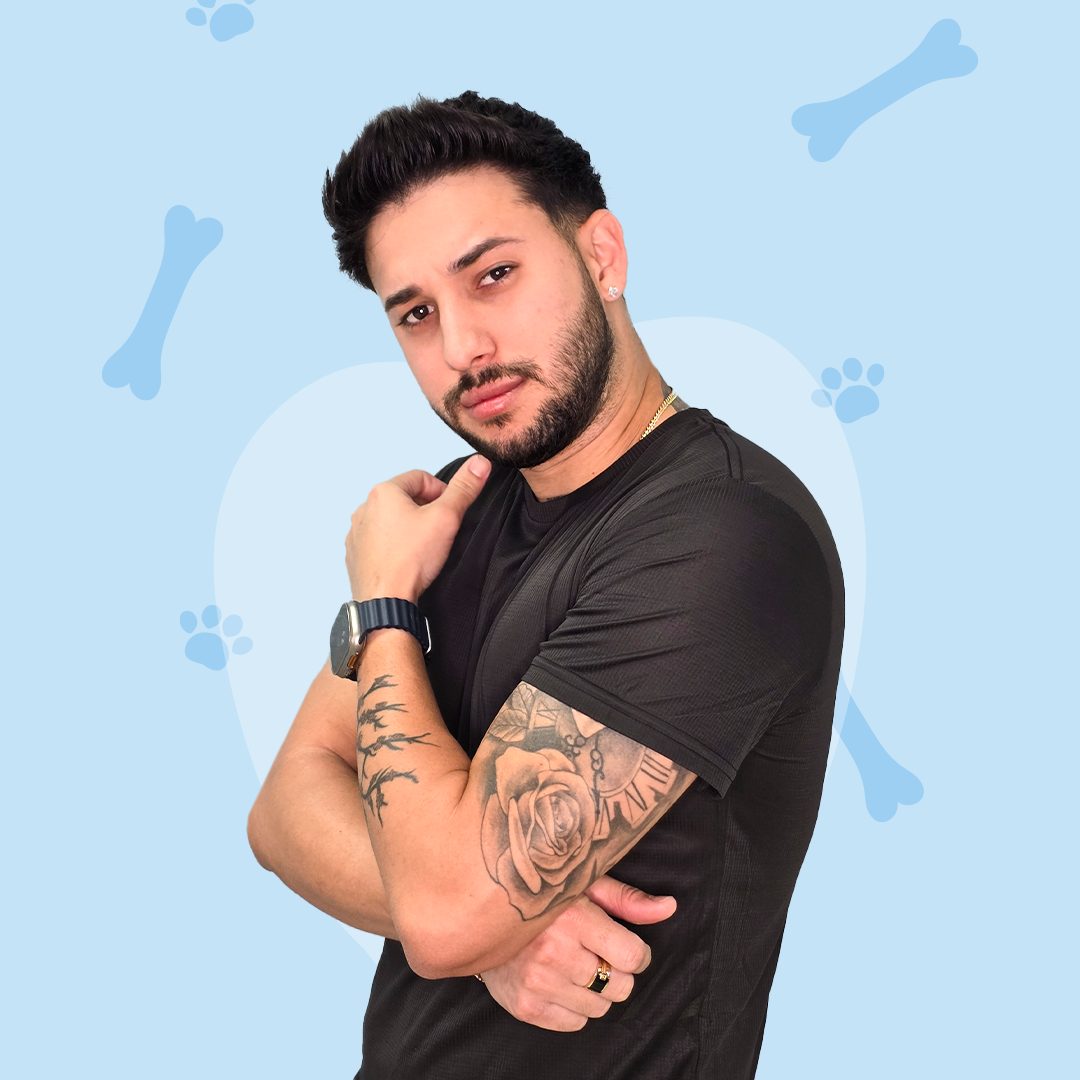 A man with a tattoo on his arm is standing with his arms crossed.