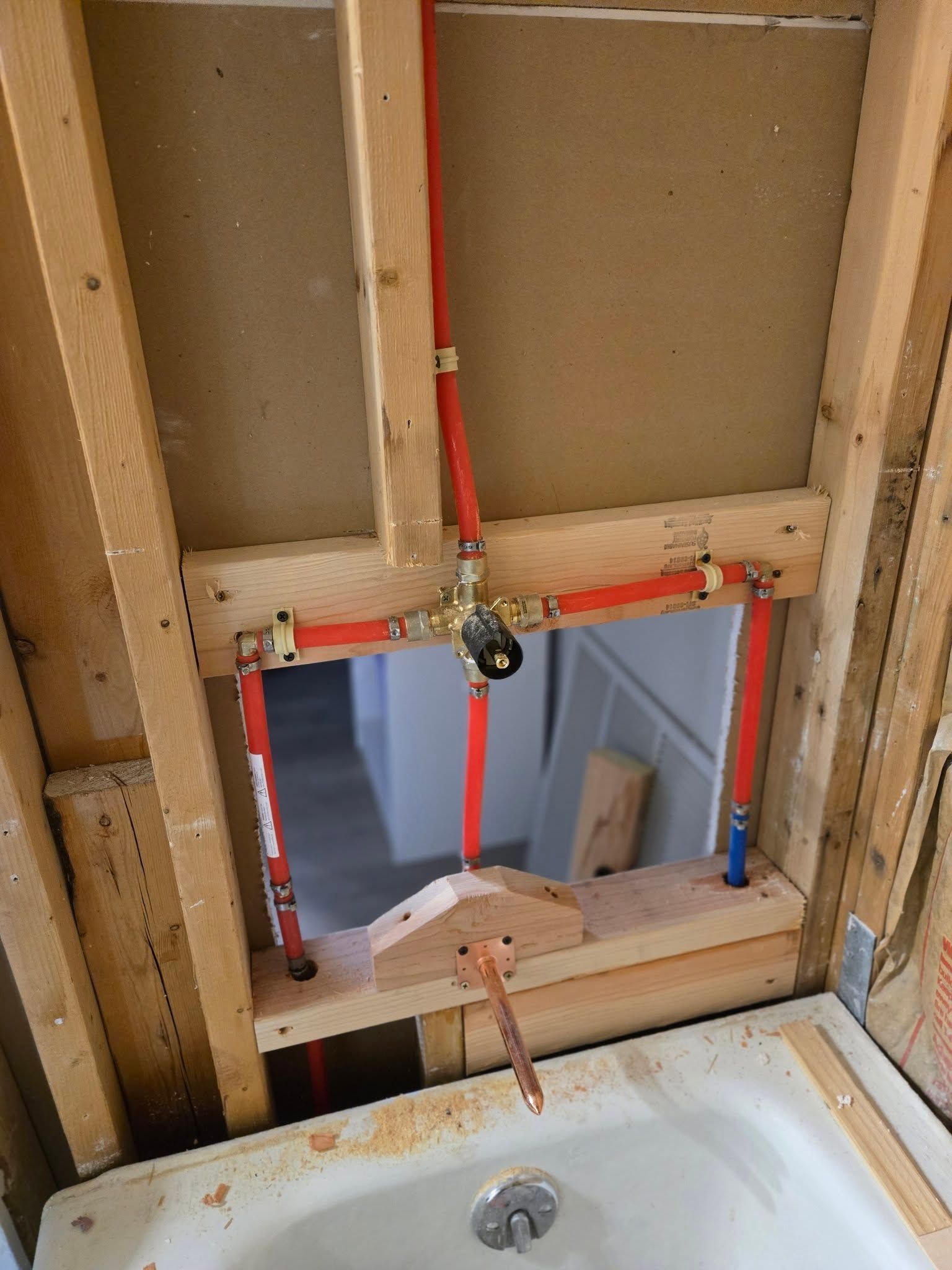 Partially finished wall with a rectangular cutout and exposed wood framing above a sink faucet