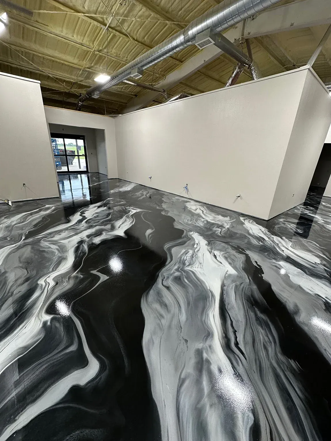 A room with a swirled black, white, and gray epoxy floor and white walls.