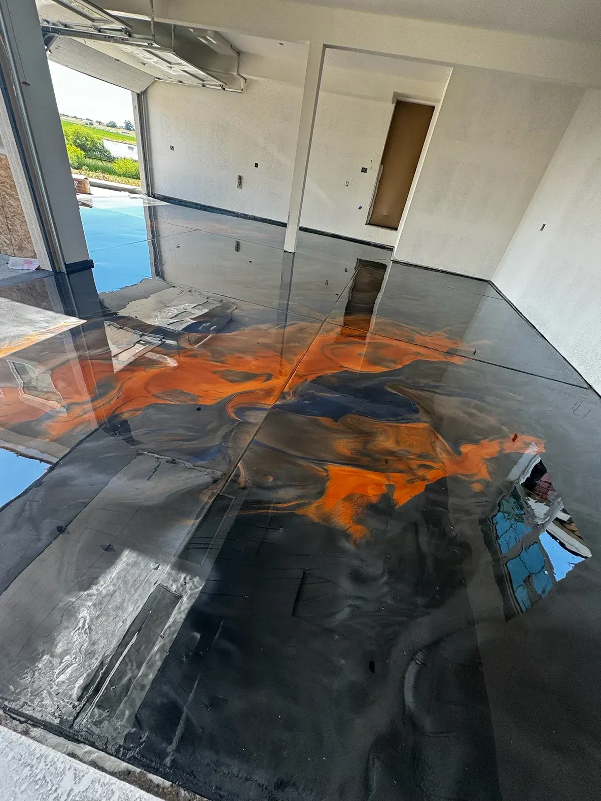 Glossy epoxy floor with black and orange swirls in a building under construction.