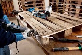 Person using power tools to cut a wooden pallet in a workshop