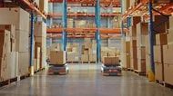 Warehouse aisle with two forklifts under tall orange and blue storage racks