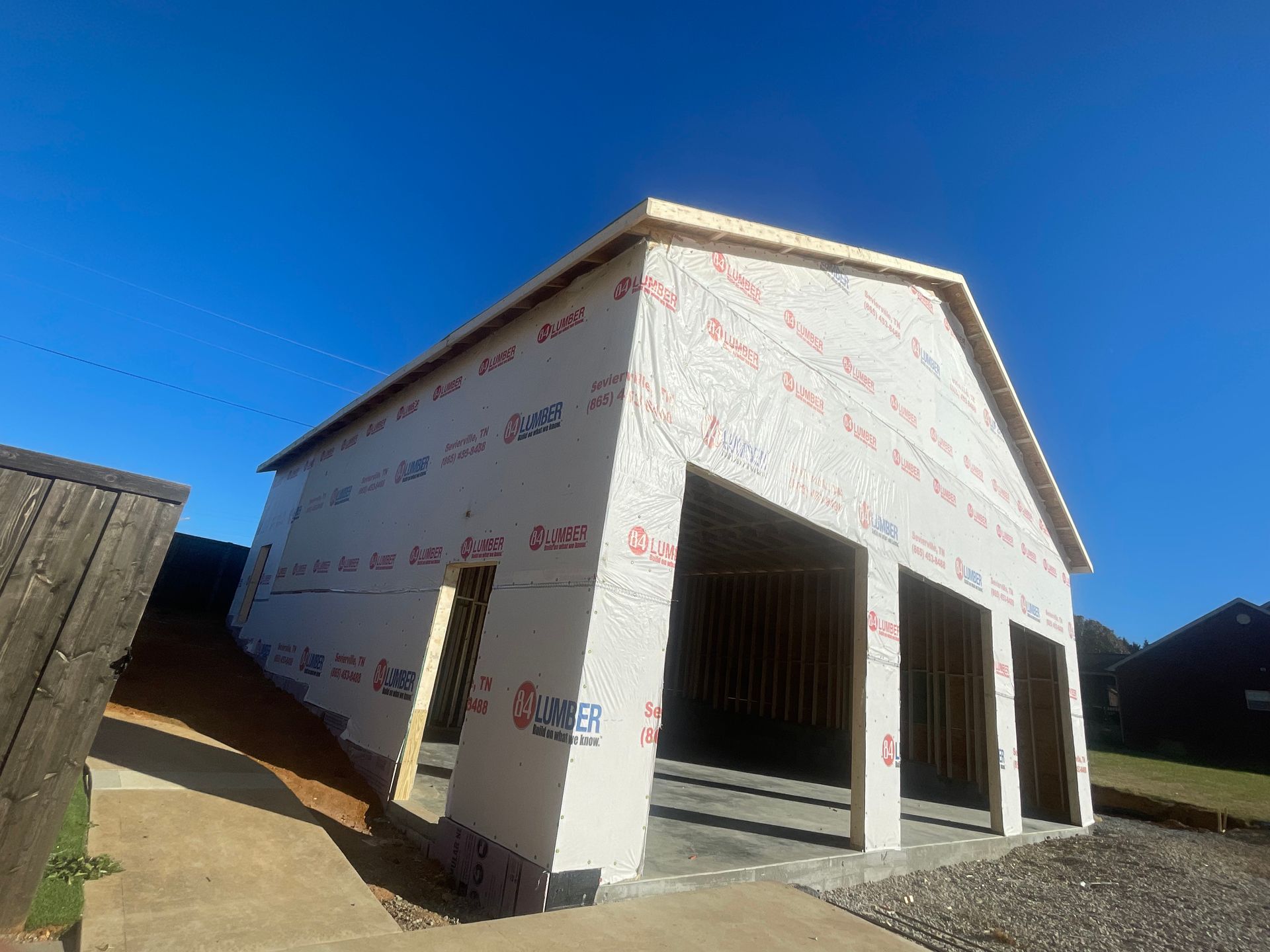 Partially built white house with open garage-style bays under a bright blue sky