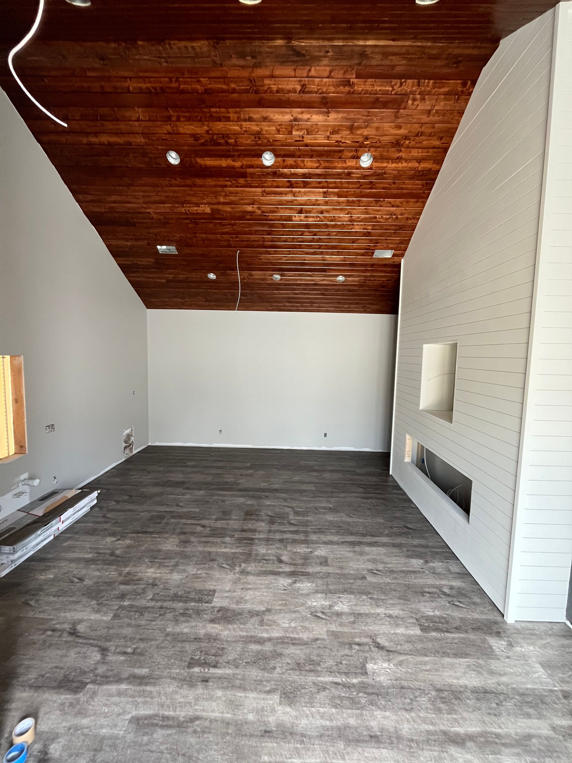 Empty living room with wood ceiling, white walls, and gray flooring