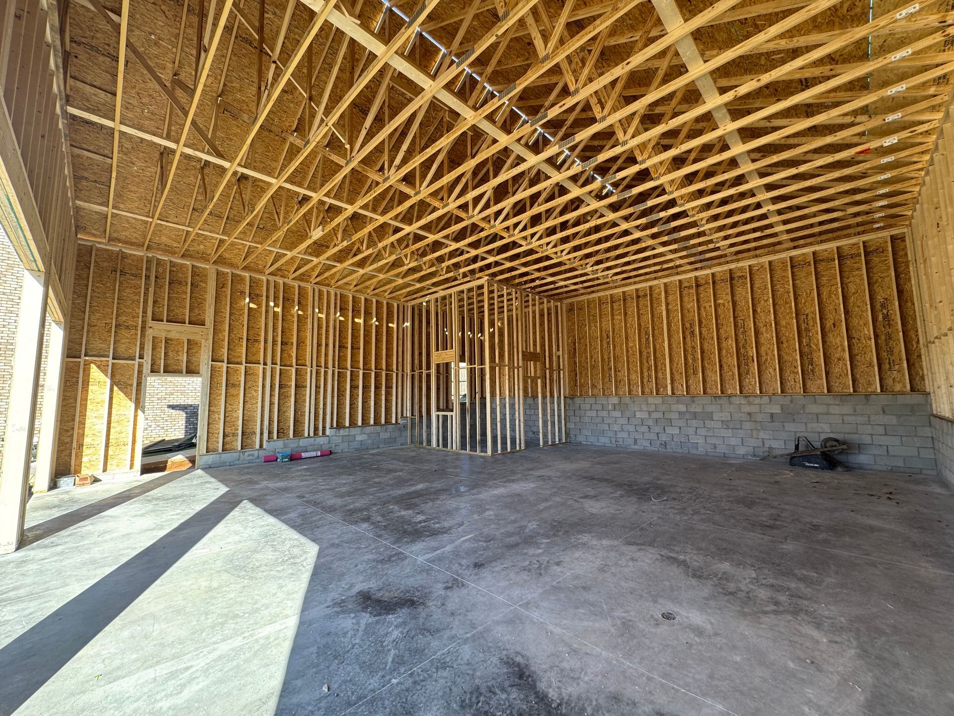 Empty unfinished wooden building interior with exposed roof trusses and concrete floor