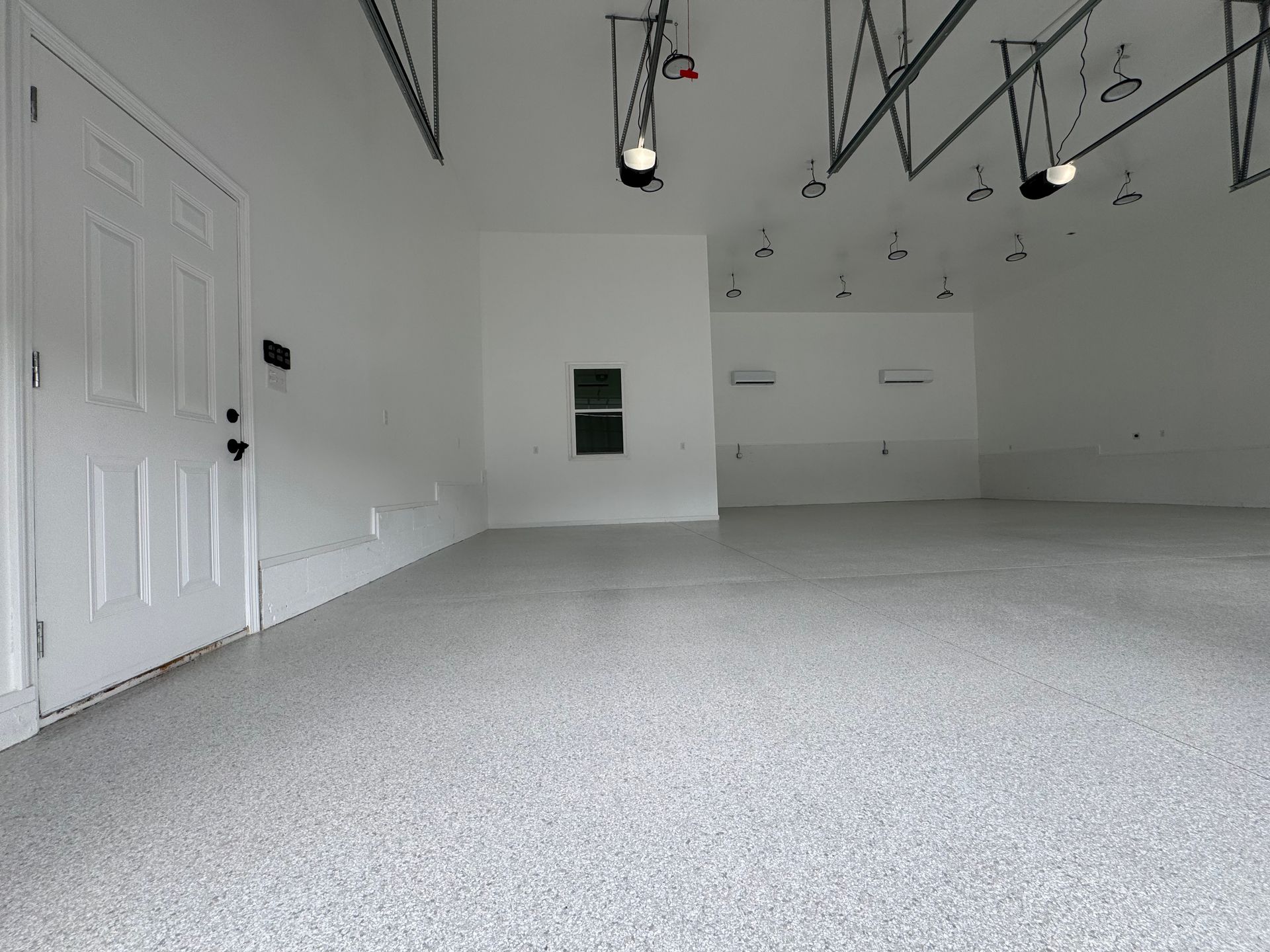 Empty white garage interior with gray floor and overhead door tracks