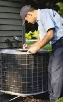 Man inspecting an outdoor air conditioning unit with tools beside a house