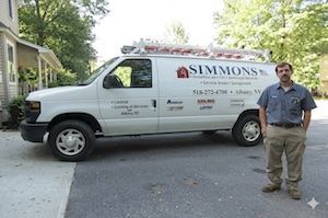 White Simmons service van parked beside a man on a driveway near a house