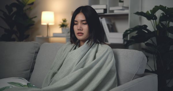 Asian Young woman suffering from cold, Sick with flu, sneezing into tissue from allergies, she has severe headache temperature, Unhealthy female getting flu virus symptom Cold and fever at home
