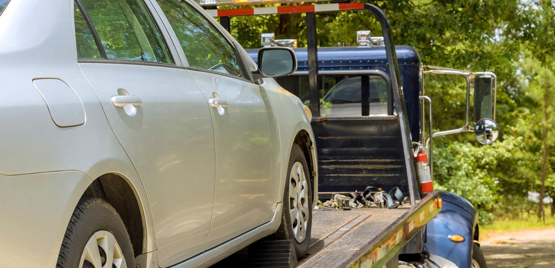 Marv’s Quality Towing Inc. delivering reliable towing services, securing a silver sedan onto a tow t