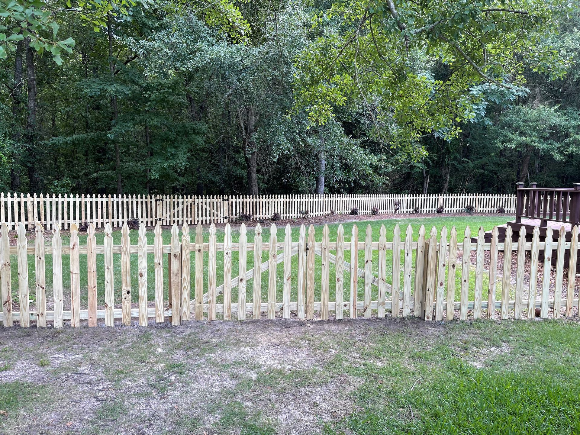 A wooden fence is sitting in the grass in front of a house.