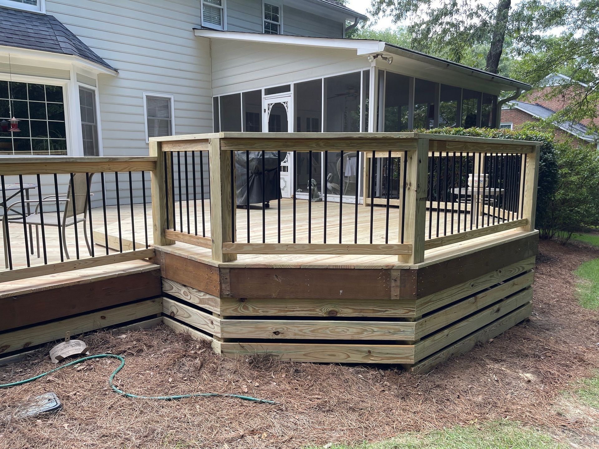 A house with a screened in porch and a wooden deck.