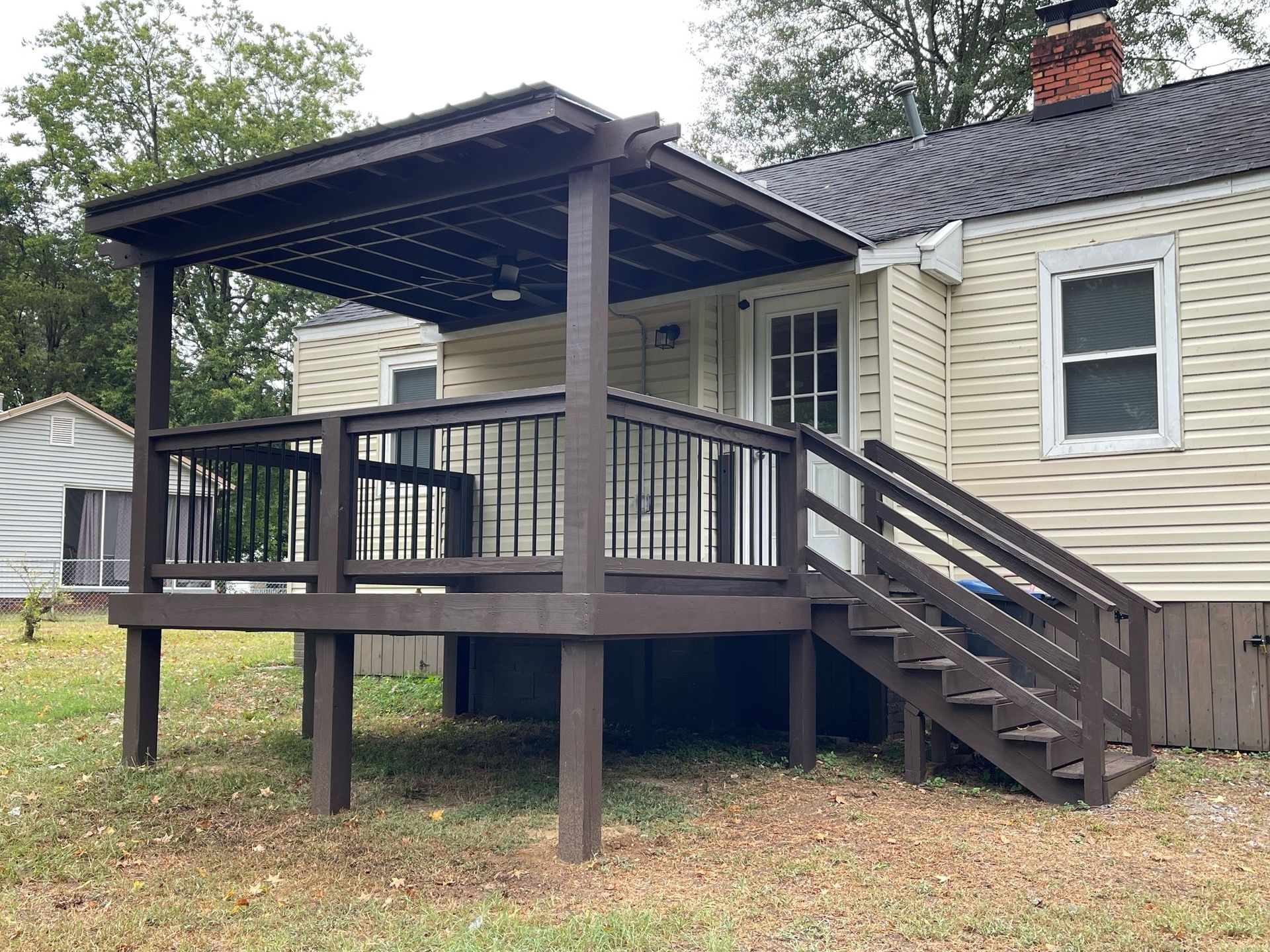 A wooden deck with a ceiling fan and a screened in porch.