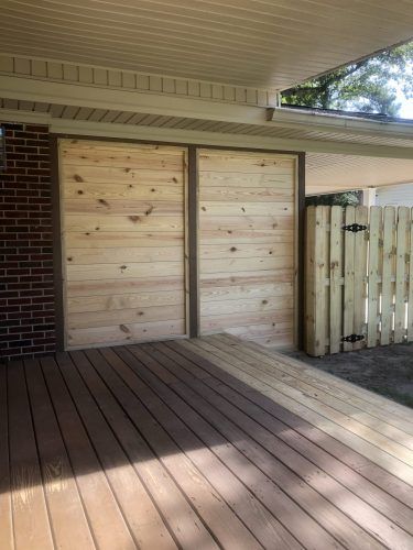 A wooden deck with a wooden fence and a wooden door.